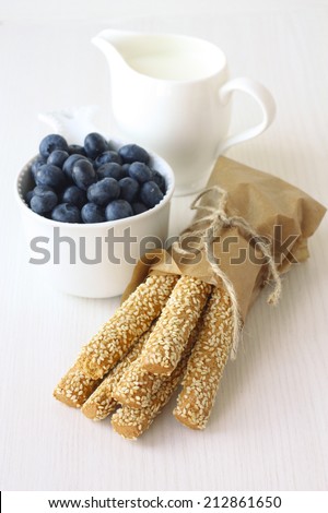 healthy breakfast: sesame sticks, blueberries and milk on white background