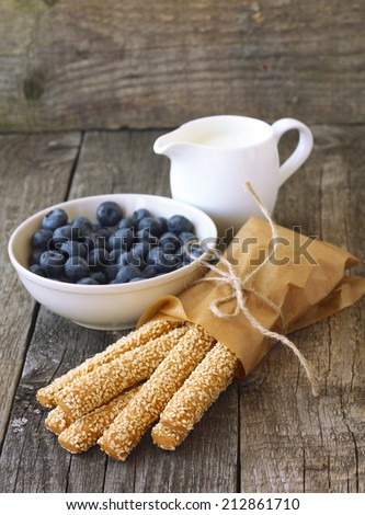 healthy breakfast: sesame sticks, blueberries and milk on wooden background