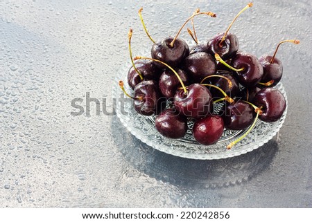 Cherries on the glass plate on  the wet background