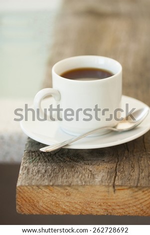 cup of hot coffee on the edge of a wooden table