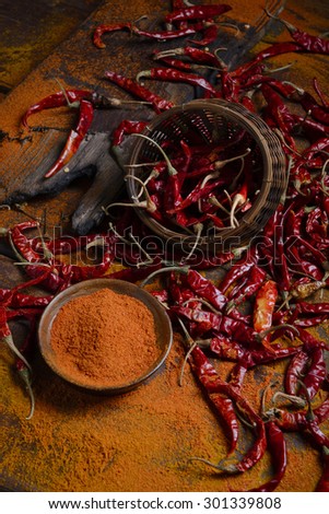 Dry chili peppers and chili powder on the dark rustic background