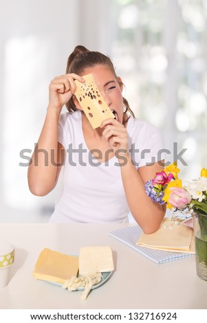 Young woman peeping through a cheese with holes