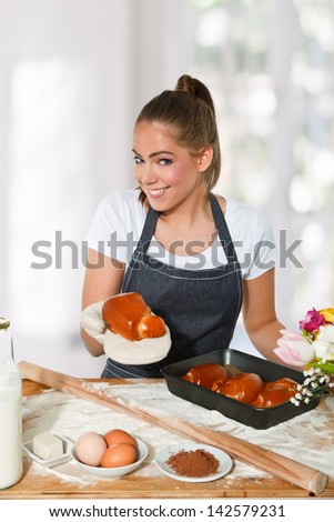 Baking woman showing a fresh homemade croissant, light backgroun