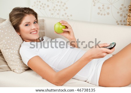 Beauty woman is eating green apple and watching TV