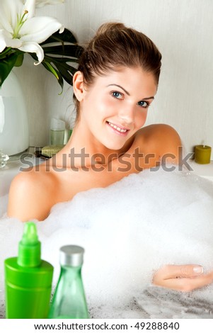 Young beauty woman smiling in the full of foam bathtub