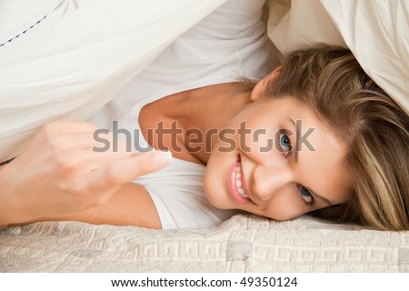 Young beauty woman couch in the bed, and calling with her finger