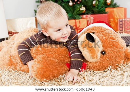Baby boy playing with a big teddy bear at Christmas