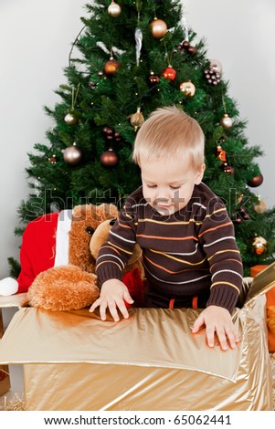 Baby boy in a christmas-box playing with a toy at Christmas
