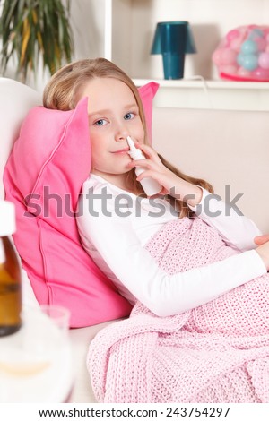 Sick little girl using nasal spray