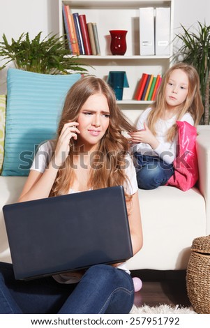 Bored child looking for attention from working busy mother