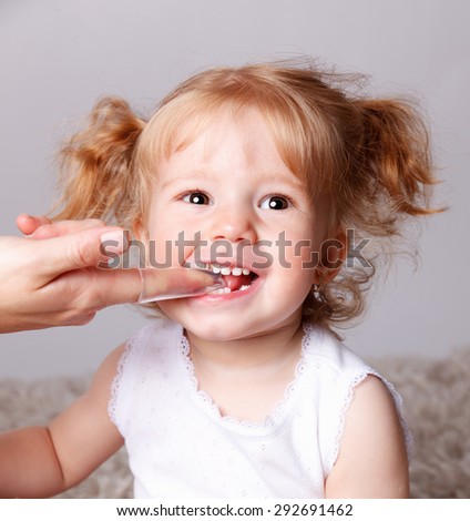 Happy little child getting her teeth brushed with finger toothbr