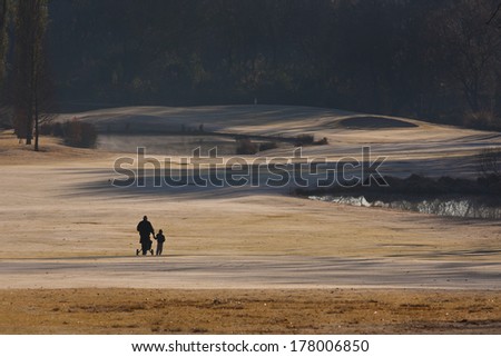 Father and son holding hands on a cold, frosty, winter morning on the golf course