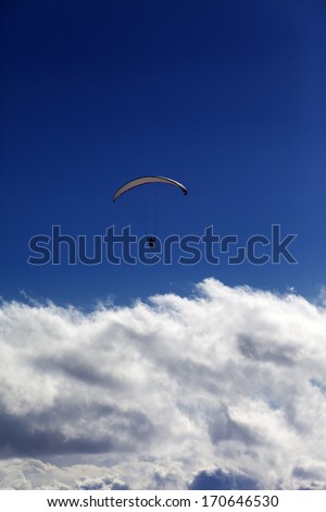 Silhouette of paraglider and blue sky with clouds. Caucasus Mountains. Georgia, view from ski resort Gudauri.