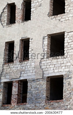 Wall of old destroyed house with broken windows