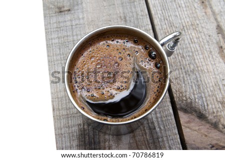 Metal mug of coffee on wooden table. Isolated on white background.