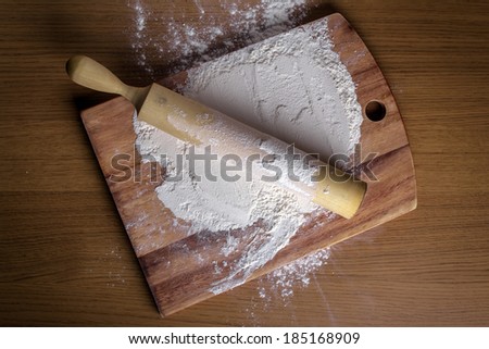 flour with a rolling pin on a cutting board