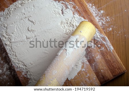 flour with a rolling pin on a cutting board.