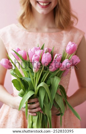 Young woman with a spring bouquet of pink tulips