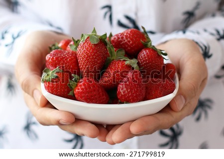 Full bowl of juicy ripe strawberries in hands