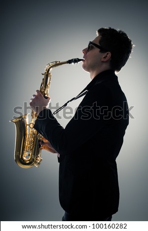 Young man playing sax in the dark