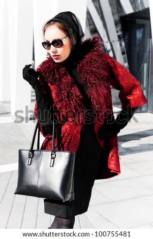 Stylish lady in bright red coat in a city scene