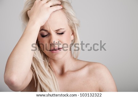 Portrait of a young woman suffering from headache on background
