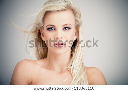 Young blond lady with a beautiful hair on gray background