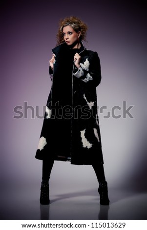 Young brunette lady in wool coat posing on purple background