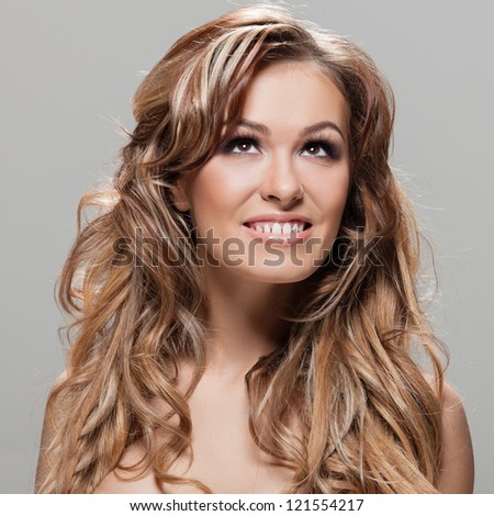 Young brunette lady with a beautiful hair on gray background