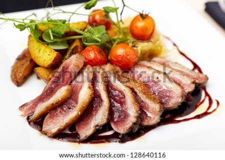 Roasted duck with cherry tomatoes and potatoes marinated in red wine