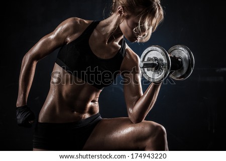 Brutal athletic woman pumping up muscules with dumbbells - stock photo