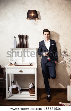 Handsome young man in a classic suit drinking red wine in restaurant
