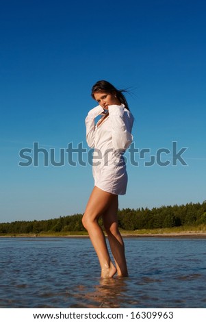Young sexy girl in wet men\'s shirt on a beach