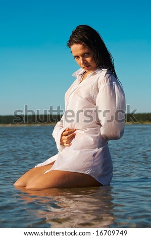Wet men\'s shirt outlines the naked body of young sexy female model
