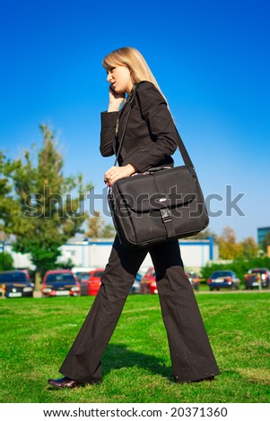 Businesswoman with laptop bag walking in the park