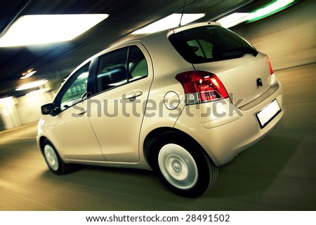 Rear view of compact hatchback driving fast in parking house