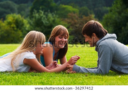 stock photo Two girls and one guy flirting in a meadow