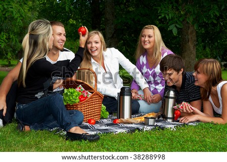 Five happy friends on picnic in a park