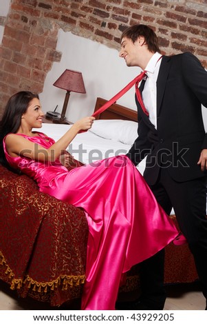 Young glamorous woman pulling a man by the red tie