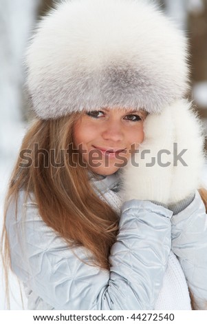 Young woman in a fur-cap in a winter forest