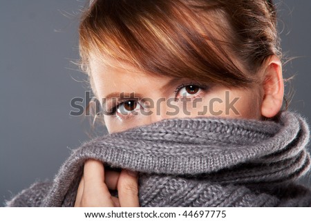 Young brunette woman in warm grey sweater hiding her face