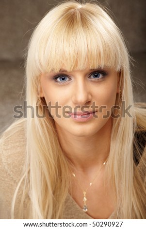 Portrait of beautiful happy lady with blue eyes in beige sweater