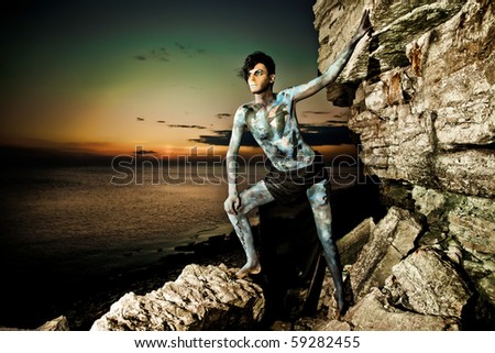 male model with bodyart posing on rocks near the sea stock photo male model with bodyart posing on rocks near the sea stock photo