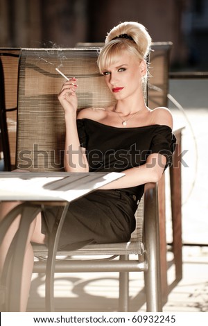 50s styled woman sitting in a street cafe and smoking cigarette
