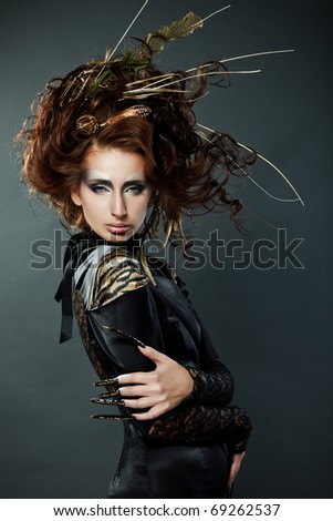 High fashion model in black dress, with long nails and creative hairstyling on grey background
