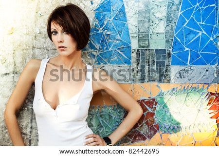 Sexy brunette lady in white shirt standing near a brick wall