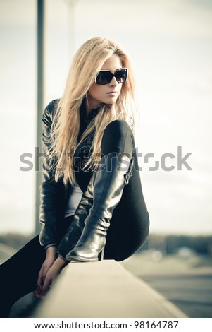Young woman in sunglasses sitting near a highway