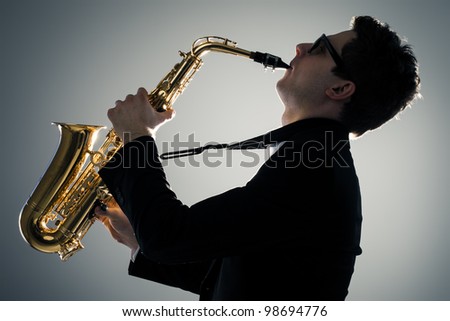 Young man playing sax in the dark