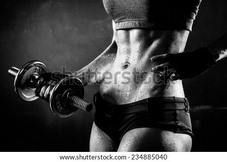 Athletic Woman Pumping Up Muscules with Dumbbells Stock Photo