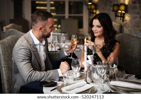 Couple with champange glasses dating and toasting in restaurant